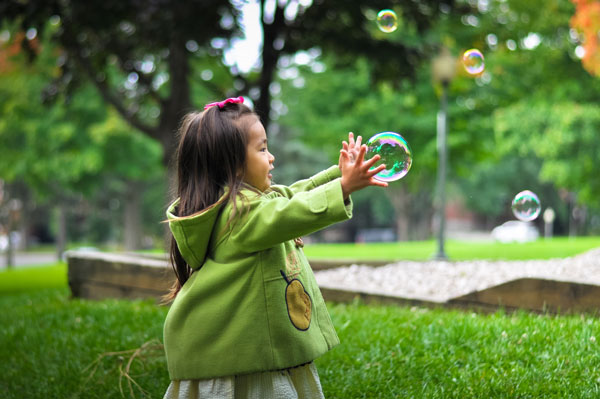 Person blowing bubbles in a green garden, representing intentional rest and strategic recovery in Lifestyle Inertia Design